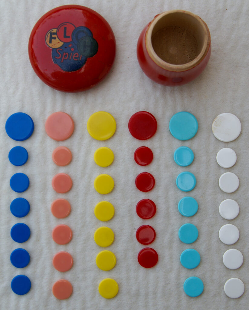 Tucker Tw ID • UNK-101c1 — AGPI ID • G-30820c1 — publisher • (unknown, German) — title • FLOH Spiel — notes • Red wooden mushroom container. Letters of "FLOH" on different colored winks.